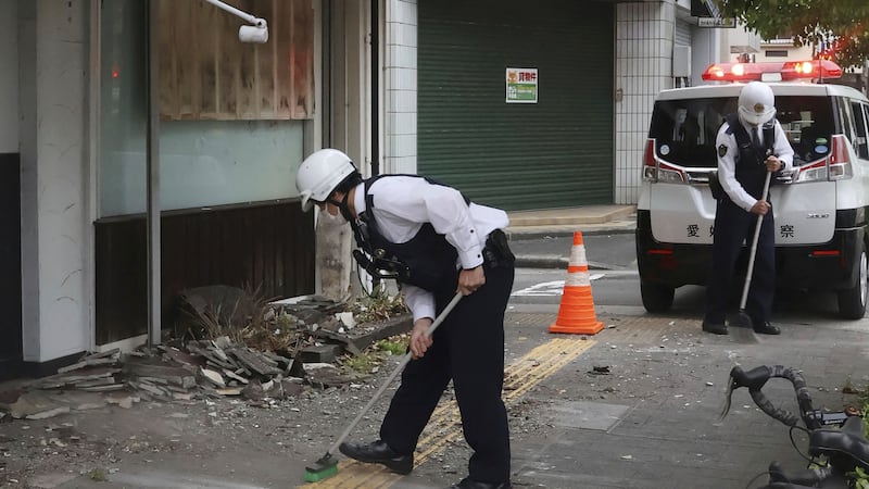 Police officers clean debris from an earthquake in Uwajima, western Japan (AP)