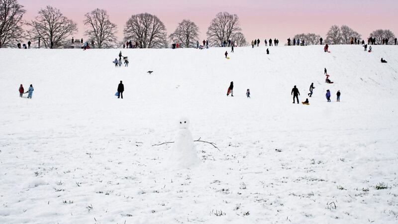 "Snowman in forground has his back to the action with Late Afternoon Family Fun in the snow against a stunning sky. Taken on Hexham Sele, Northumberland, England".