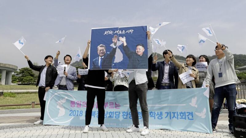 South Koreans pose for the media as they hold a banner showing the pictures of South Korean president Moon Jae-in, left, and North Korean leader Kim Jong Un to welcome the planned summit between South and North Koreas near the presidential Blue House in Seoul, South Korea. Picture by Lee Jin-man, Associated Press 