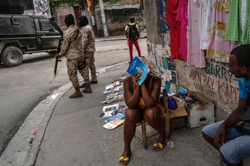 Police officers patrol next to a street vendor in Port-au-Prince (Ramon Espinosa/AP)