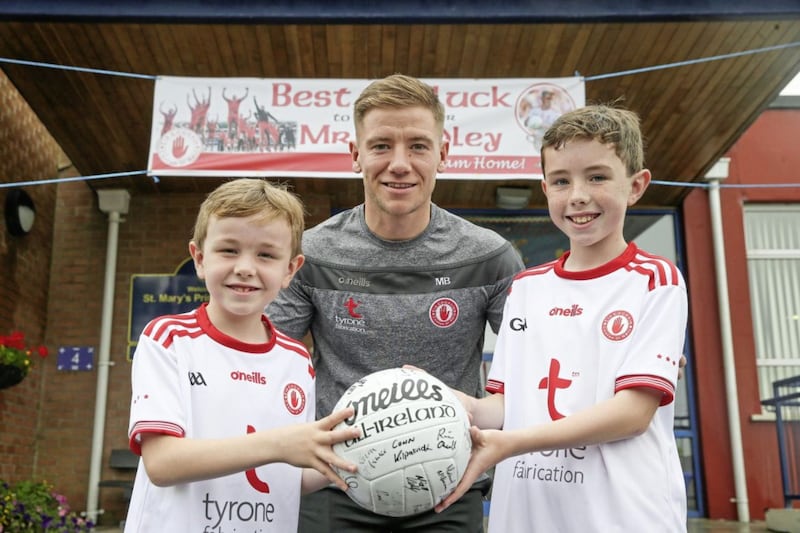 Conall and Eoin Bonner, pupils at St Mary&#39;s Primary School in Pomeroy, with teacher and Tyrone footballer Mark Bradley, who donated a ball signed by the team for a school raffle. Picture by Hugh Russell 
