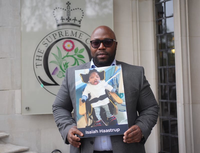 Lanre Haastru hold a picture of his son, Isaiah Haastrup, outside the Supreme Court
