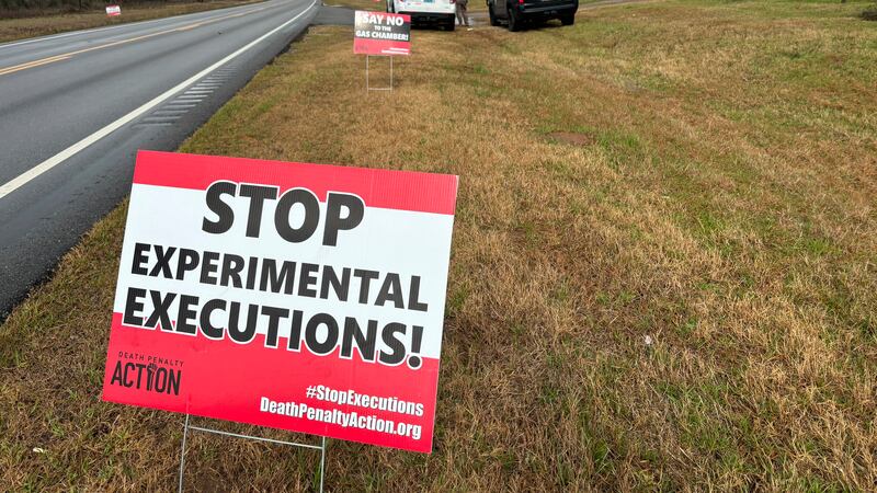 Anti-death penalty activists place signs along the road heading to Holman Correctional Facility in Atmore ahead of the scheduled execution of Kenneth Eugene Smith on Thursday (Kim Chandler, AP)
