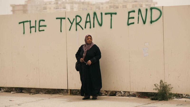A woman beneath graffiti prophesising the end of Moammar Gadhafi&#39;s regime after his 42-year rule 
