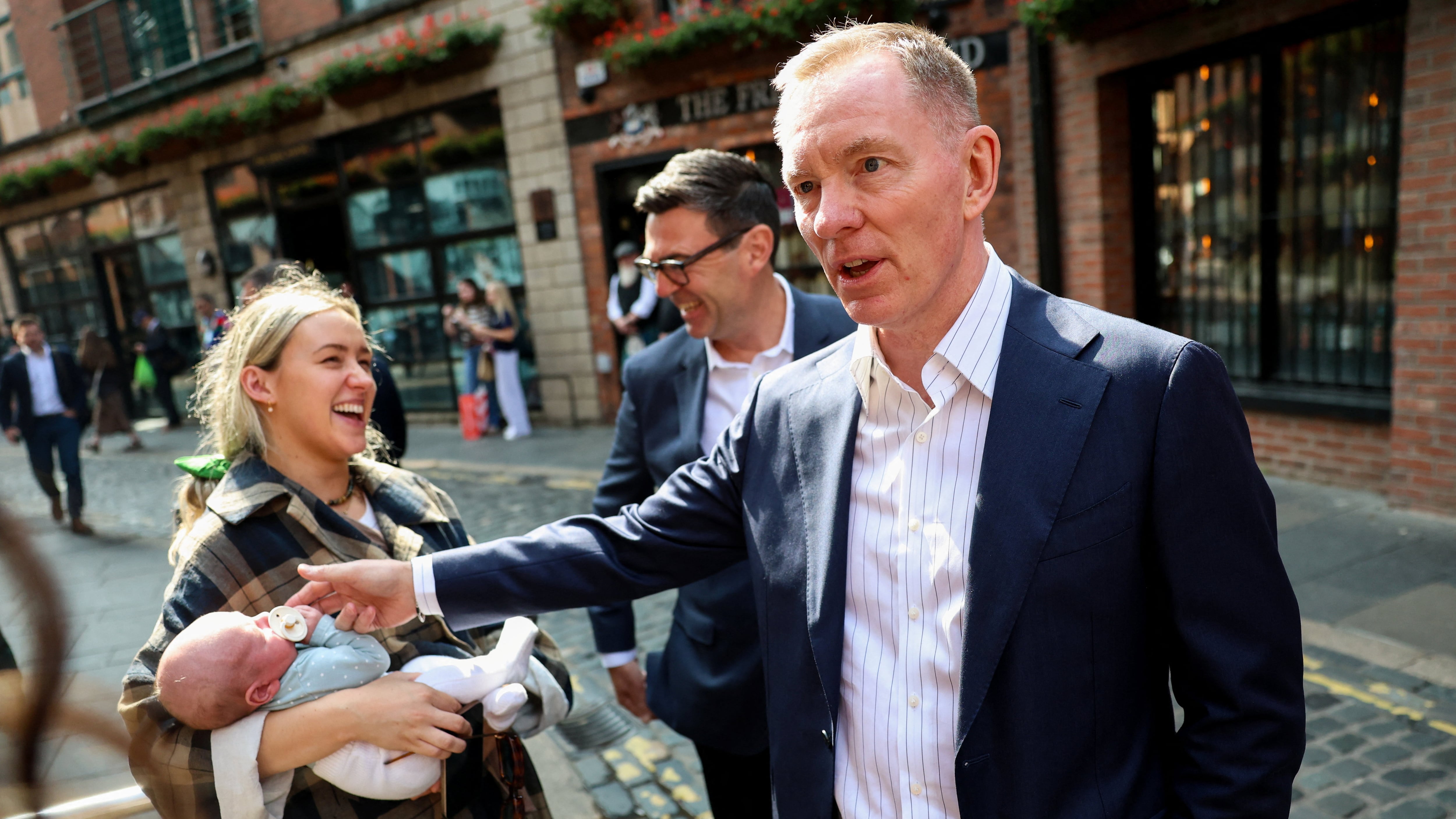 Prime Minister Andy Burnham (centre), and Northern Ireland Secretary Sir Chris Bryant (right), speak with locals in Belfast