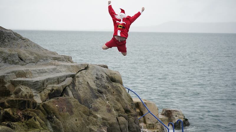 Patrick Corkery dressed as Santa and his son Matthew, 12, dressed as an elf, taking part in the annual Christmas Day swim at the Forty Foot bathing spot in Sandycove Dublin