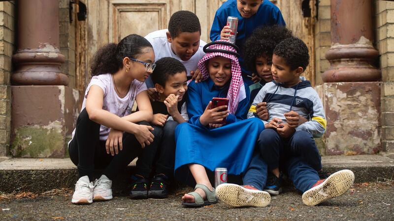 At the Iqraa masque, a group of children watch cartoons on a phone during the back to school bazaar. Picture Mark Marlow