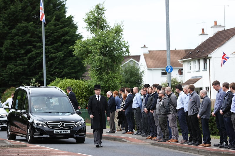Employees stand outside the Wrightbus factory in Ballymena, as they watch the passing cortege ahead of the funeral service for the founder of WireWrightbus, Sir William Wright