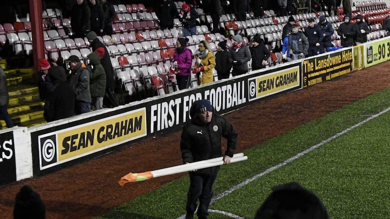 A Cliftonville steward collects the corner flags after the early abandonment at Solitude 