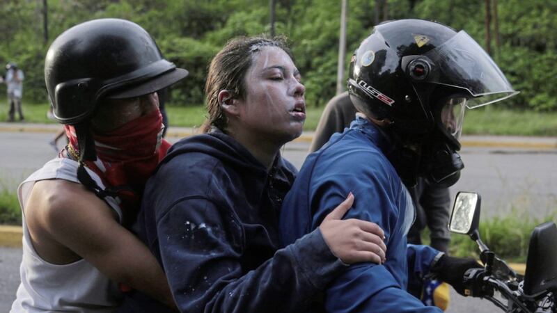 A demonstrator affected by tear gas is evacuated during clashes with the Bolivarian National Guard, at El Hatillo municipality outside Caracas, Venezuela Picture Fernando Llano/AP 