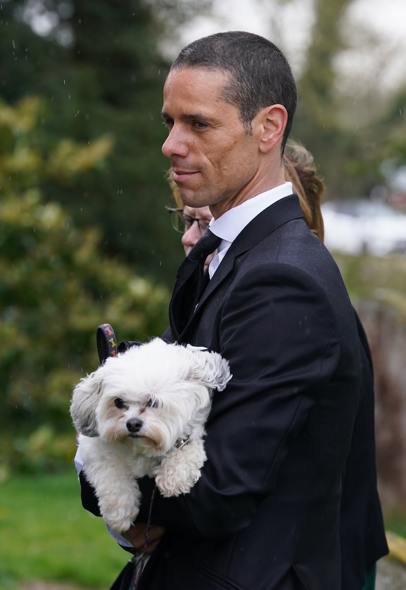 Andre Portasio, carrying one of their dogs, arriving for the funeral of Paul O’Grady in Kent