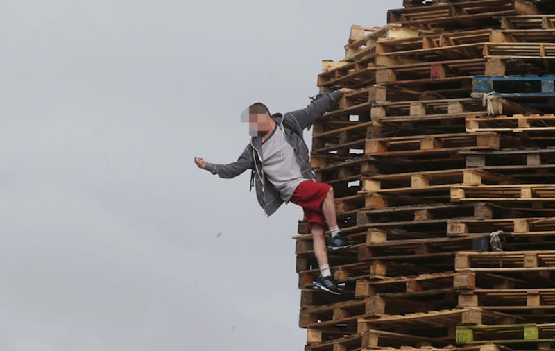 A youth climbs towards the top of the New Lodge bonfire. Picture by Hugh Russell&nbsp;