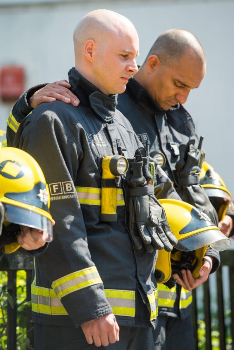 Firefighters observe a minute's silence near Grenfell Tower (Dominic Lipinski/PA)