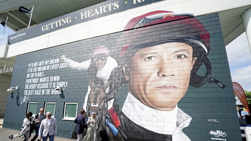 Race goers walk past the mural tribute to Frankie Dettori on ladies day of the 2023 Derby Festival at Epsom Downs 