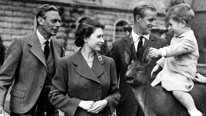 The Queen with her father, King George VI, and Prince Philip watching a young King Charles sitting on a statue at Balmoral in 1951