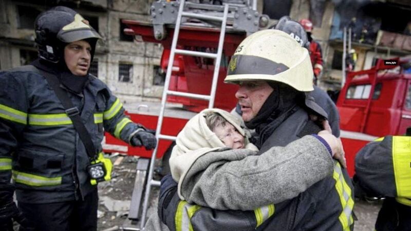 A firefighter hugs an elderly woman after she was evacuated from an apartment building hit by shelling in Kyiv, Ukraine, yesterday. Picture by Ukrainian State Emergency Service, Associated Press 