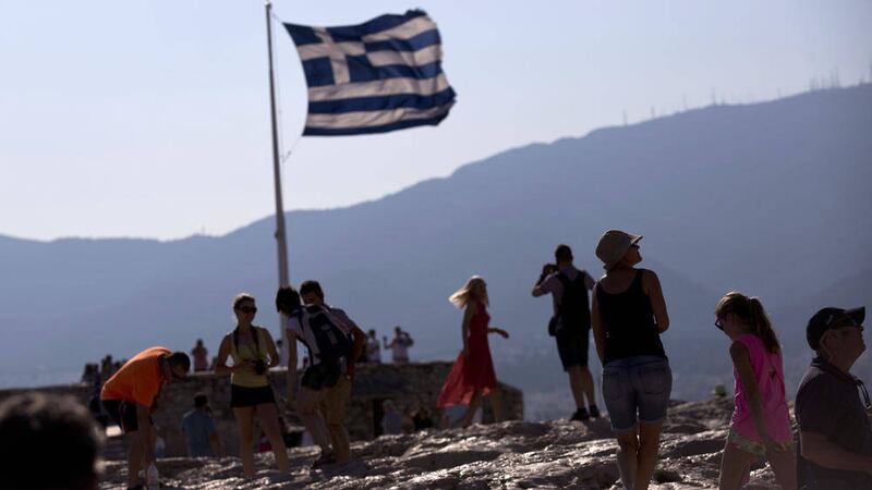 A Greek flag waves behind tourists at the ancient Acropolis hill, in Athens 