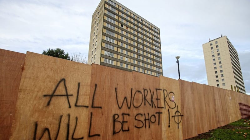 Dozens of workers have downed tools in the loyalist Rathcoole estate in Newtownabbey after death threats against them were sprayed on nearby hoardings. 