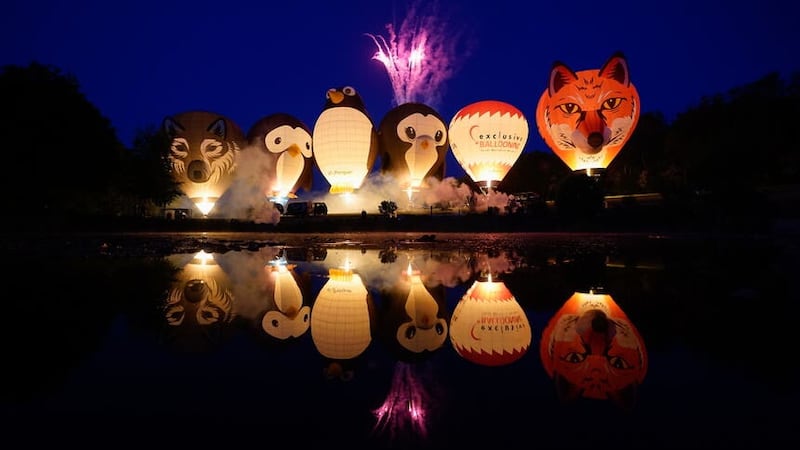 Balloons light up as they are tethered to the ground during the night glow at the Isle of Wight Balloon Festival at Robin Hill Country Park (Andrew Matthews/PA)
