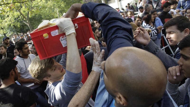 Migrants take food from volunteers as they wait at a reception centre in Berlin. Picture by Markus Schreiber/AP 