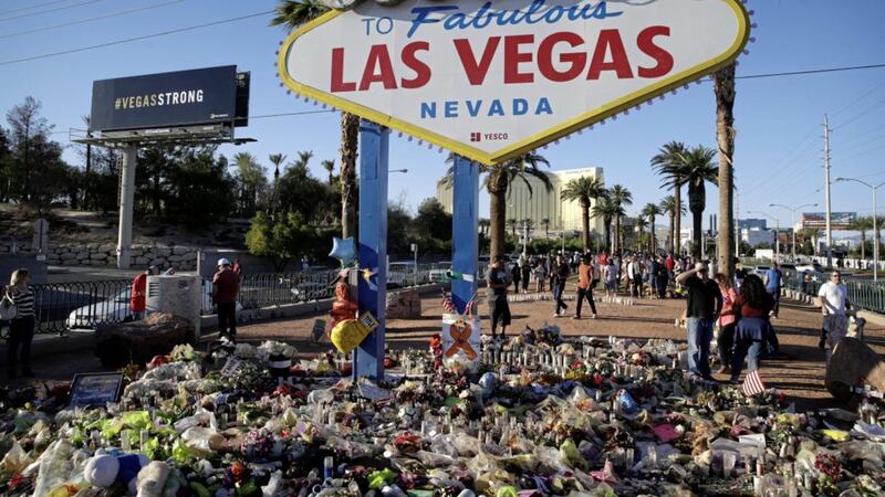 Flowers, candles and other items surround the famous Las Vegas sign at a makeshift memorial for victims of a mass shooting PICTURE: John Locher/AP 