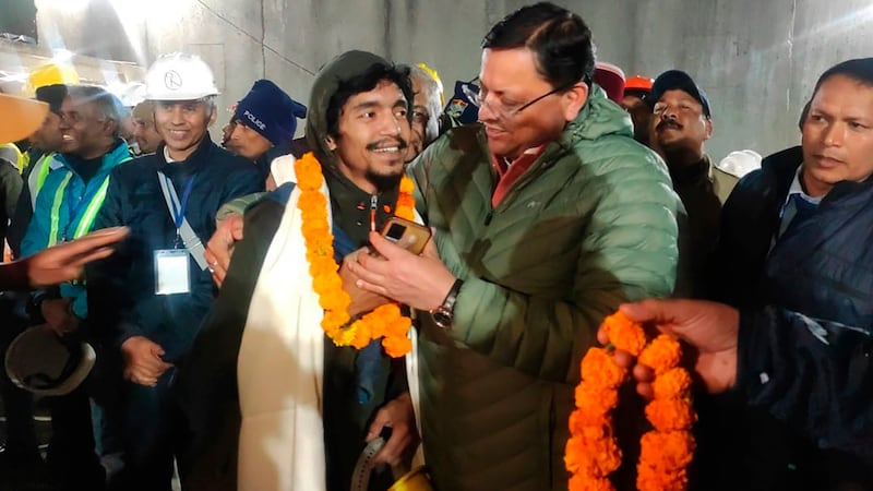 Pushkar Singh Dhami, right, chief minister of the state of Uttarakhand, greeting a worker rescued from the site of an under-construction road tunnel that collapsed in Silkyara in the northern Indian state of Uttarakhand, India (Uttarakhand State Department of Information and Public Relations via AP)