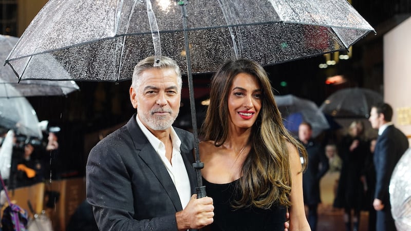 George and Amal Clooney bared the British storms as they took to the red carpet for a special screening of his new film The Boys In The Boat (Ian West/PA)