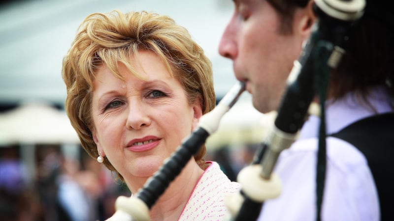Then-Irish president Mary McAleese listens to a piper play in the grounds of Aras an Uachtarain