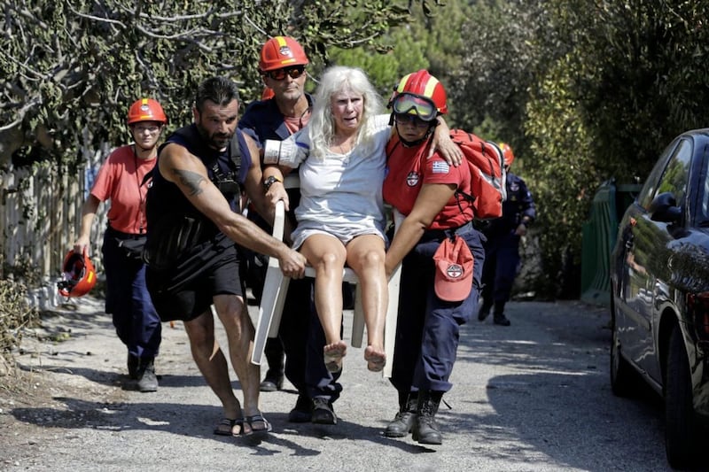 Members of a rescue team carry an injured woman in Mati, east of Athens. Picture by Thanassis Stavrakis, Associated Press
