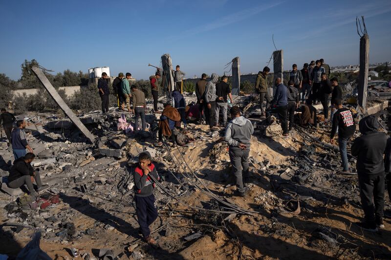 Palestinians search for bodies and survivors in the rubble of a house destroyed in an Israeli airstrike in Rafah (Fatima Shbair/AP)