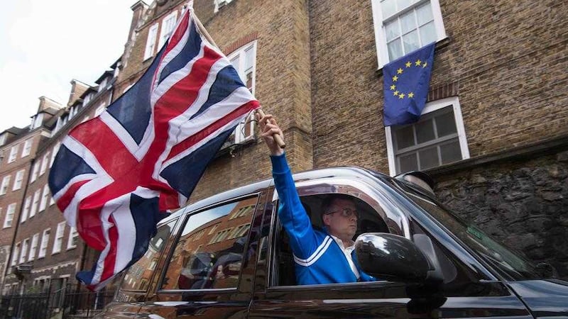 A London taxi driver waves a Union flag in Westminster, London after the UK voted to leave the European Union 