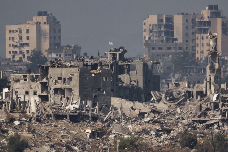 An Israeli flag stands on the top of a destroyed building in the Gaza Strip, as seen from southern Israel (Leo Correa, AP)
