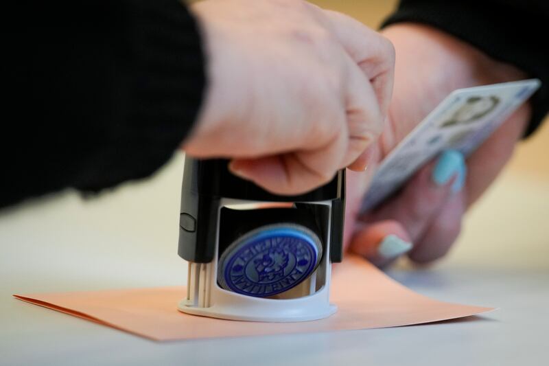 A member of an electoral committee stamps a ballot at a polling station in Helsinki (Sergei Grits/AP)