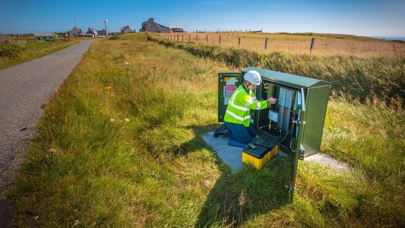 An engineer working on a traditional green street cabinet for broadband
