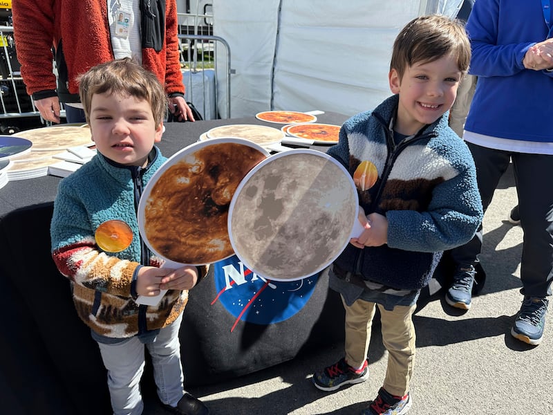 Gabriel Kauffman, four, and his brother, Theodore, six, demonstrate a total solar eclipse at a Nasa booth at the Great Lakes Science Centre in Cleveland (Stephanie Nano/AP)