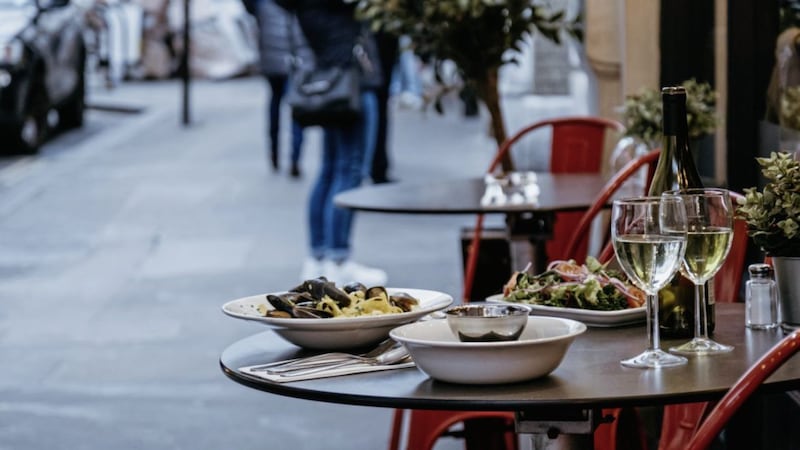 Plates with food and glasses of wine at the outdoor table of a restaurant, selective focus. 