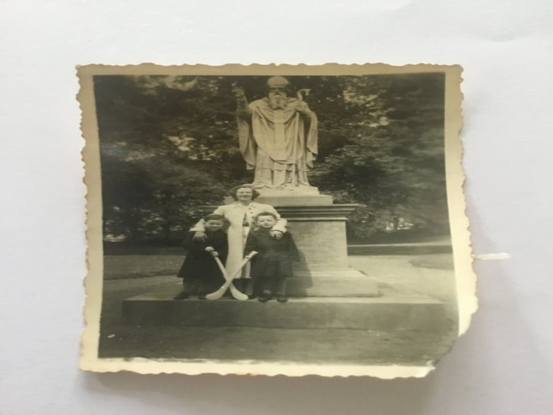 A photo of Patrick McKay and his brother Joseph, both holding camáns, standing in front of the statue of St Patrick's in Kilkenny during a family visit to Ireland in 1957