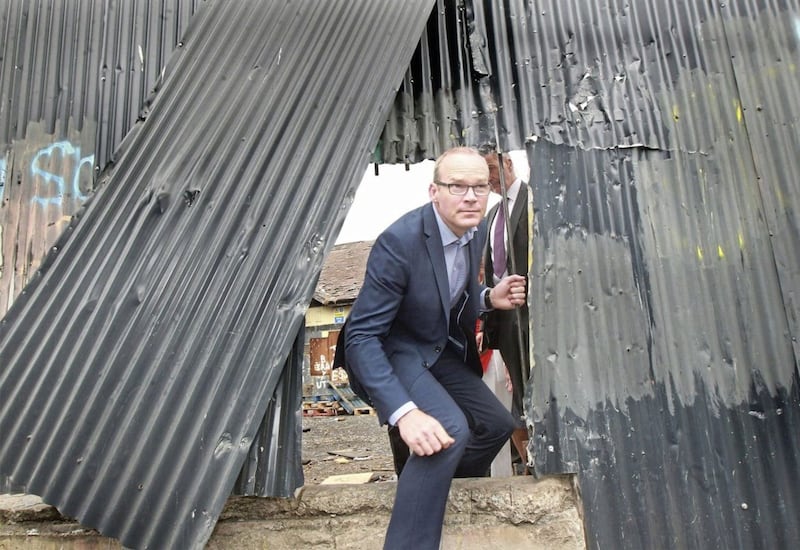 T&aacute;naiste Simon Coveney climbs out of an area of waste ground in Derry's Bogside where youths gathered during violence in the city. Picture by Margaret McLaughlin