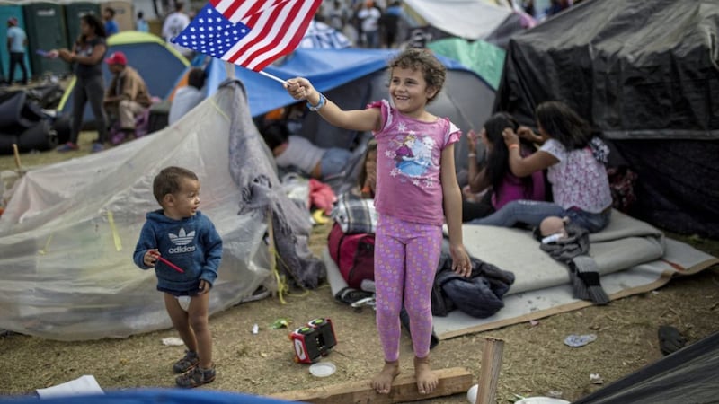 Honduran migrant Genesis Belen Mejia Flores (7) waves an American flag at US border control helicopters flying overhead near the Benito Juarez Sports Centre which was serving as a temporary shelter for Central American migrants, in Tijuana, Mexico, in November 2018. Picture by Rodrigo Abd, Associated Press 