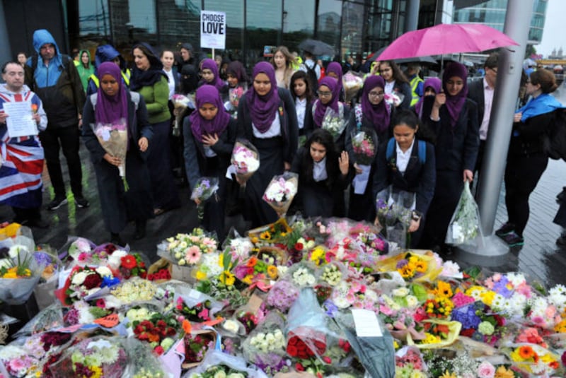 chool girls look at flowers at a vigil in Potters Fields Park, central London, in honour of the London Bridge terror attack victims.