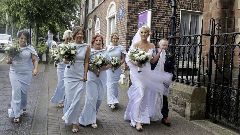 Bride Frances Nugent walks to her wedding in St Patrick&#39;s Church on Donegall Street in Belfast with her father Jim and bridesmaids. Picture by Hugh Russell 