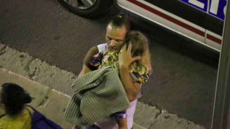 &nbsp;A man holds a child after a truck plowed through Bastille Day revelers in the French resort city of Nice, France, Thursday, July 14, 2016. France was ravaged by its third attack in two years when a large white truck mowed through revelers gathered for Bastille Day fireworks in Nice, killing at dozens of people as it bore down on the crowd for more than a mile along the Riviera city's famed seaside promenade. (Sasha Goldsmith via AP)