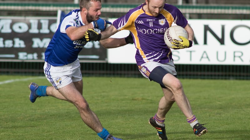 Derrygonnelly's Paul Ward holds off a challenge from Devenish corner-back Vincent O'Brien