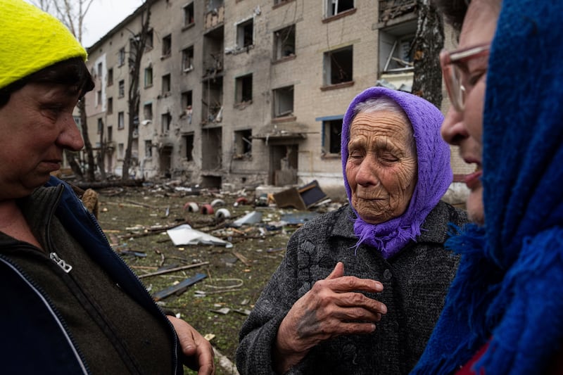 An elderly woman cries as she says goodbye to her neighbours in front of her house in Lukiantsi, which was heavily damaged by a Russian air strike (Evgeniy Maloletka/AP)