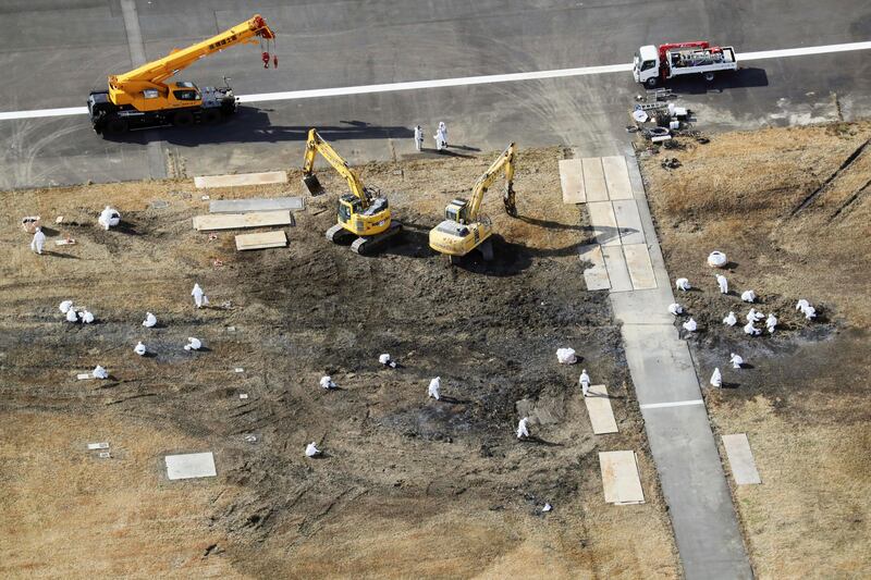 Workers at the site of a fatal runway crash at Haneda airport in Tokyo (Kyodo News via AP)