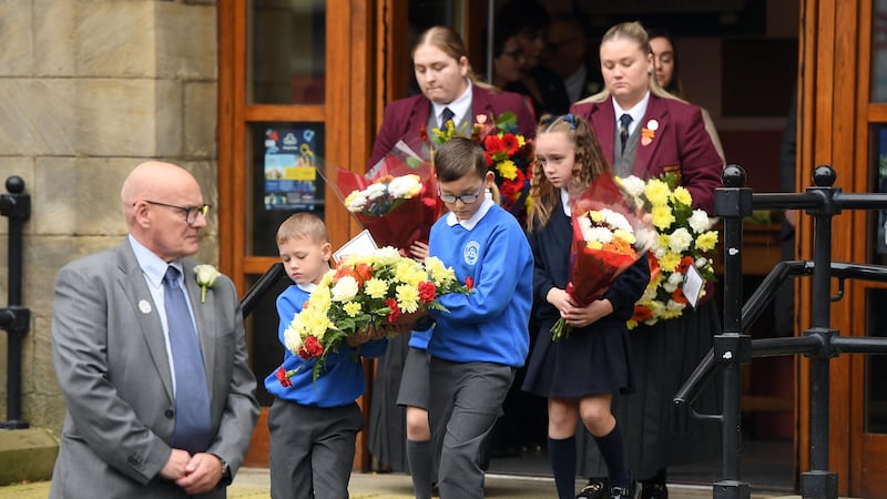 Pupils before laying floral tributes at the memorial lamp in the Shankill Memorial Park in Belfast to mark the 30th anniversary of the Shankill bomb (Oliver McVeigh/PA)