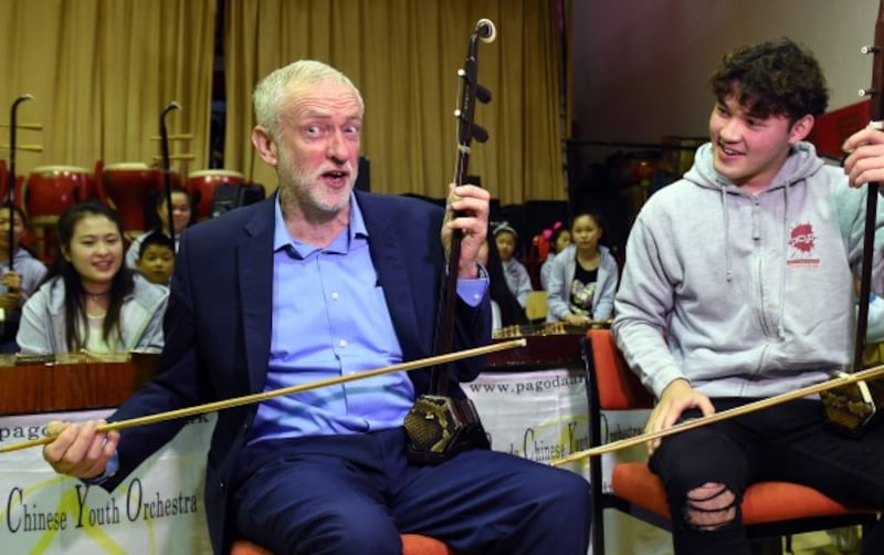 Labour leader Jeremy Corbyn (left) with Charlie Wardle, 17, playing an erhu during a community visit to Pagoda Arts in Liverpool