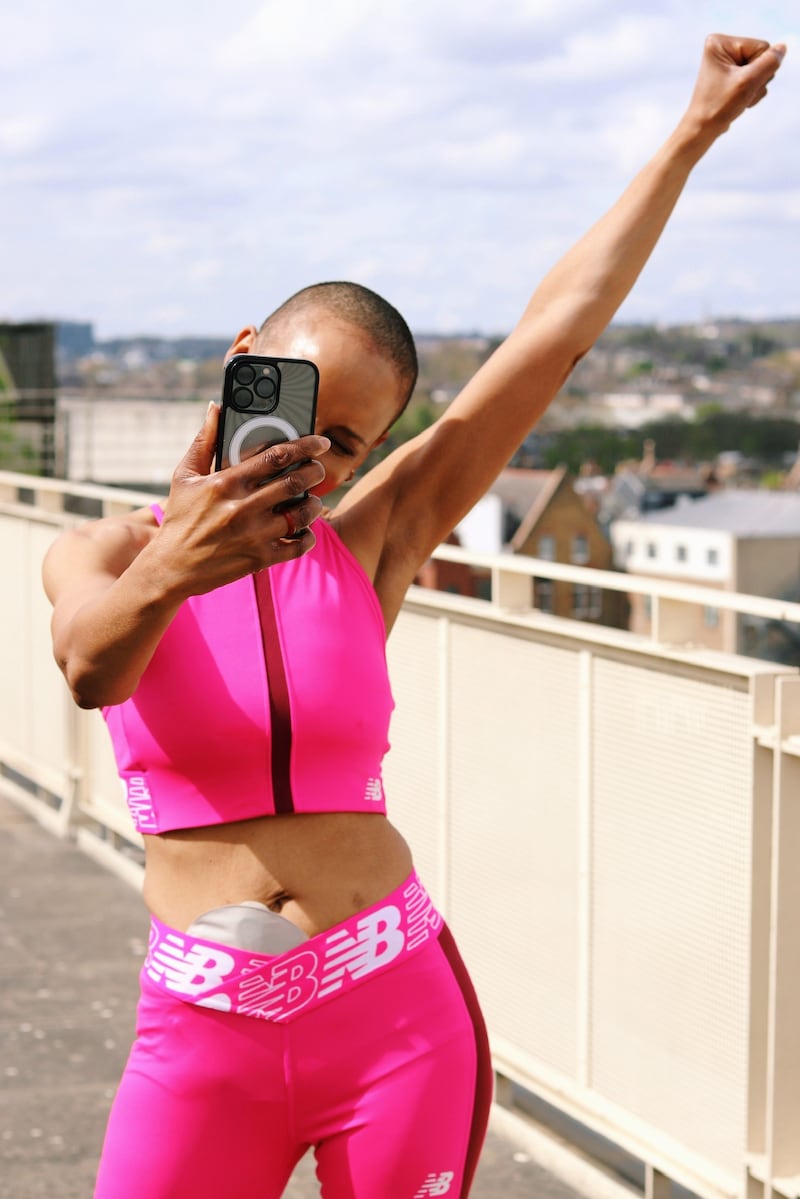 Woman wearing a pink outfit and posing with a phone
