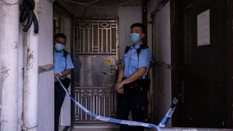Police officers stand outside an apartment where three children were killed in Sham Shui Po in Hong Kong (Louise Delmotte/AP)