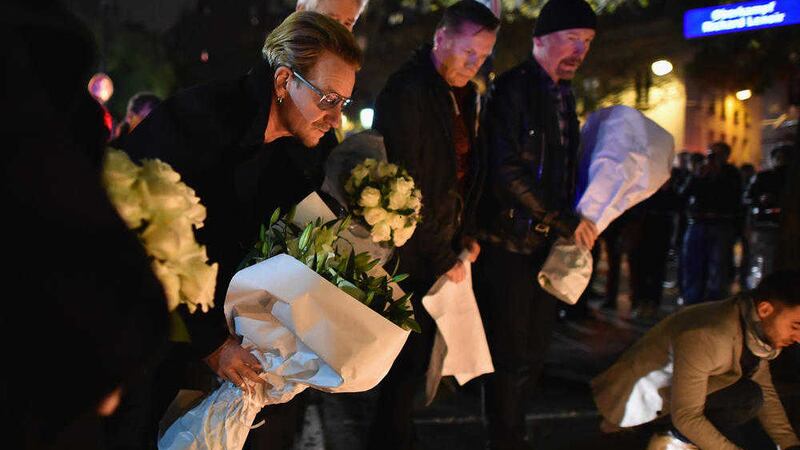 Bono, left, and fellow U2 band members lay flowers on Saturday near the scene of the Bataclan Theatre attack Picture by Jeff J Mitchell/Getty Images 